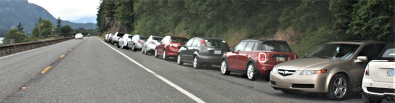 A long line of cars parked illegally on the shoulder of State Route 14.